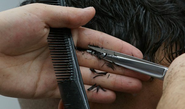 Close-up of a detailed haircut being done in a barber's chair.