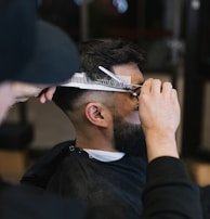 A barber carefully styling a client's hair with a comb.