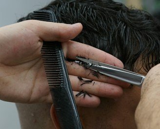 Close-up of a detailed haircut being done in a barber's chair.