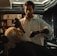 A barber carefully styling a man's beard in a well-lit salon.