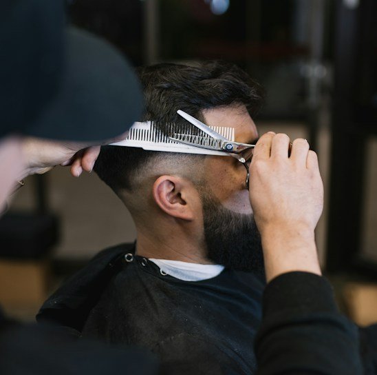 A barber skillfully trimming a man's beard in a stylish salon.