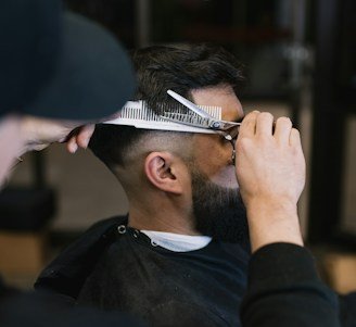 A barber skillfully trimming a man's beard in a stylish salon.