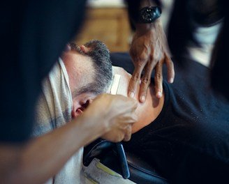 A barber gently shaving a man's beard with a straight razor.